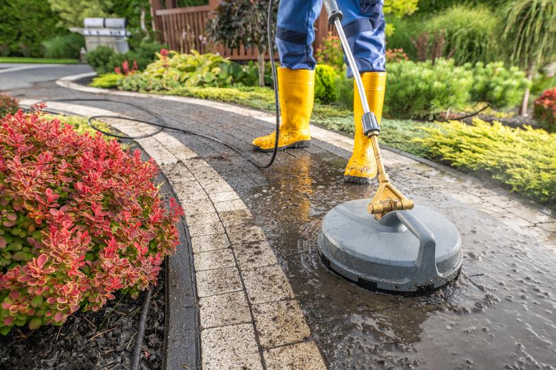 A pressure washing professional cleaning a driveway