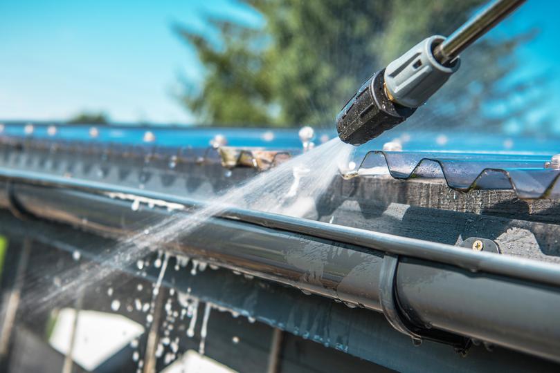 A gutter cleaning professional cleaning gutters on a house