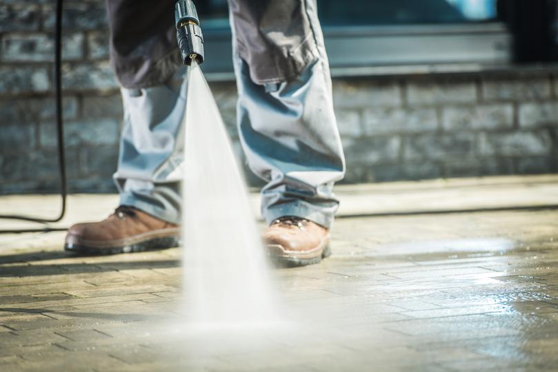 A pressure washing professional cleaning a driveway