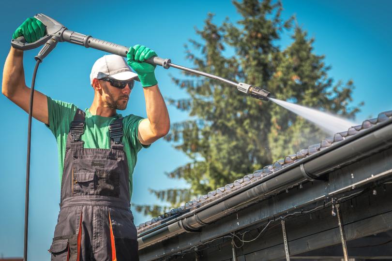 A gutter cleaning professional cleaning gutters on a house