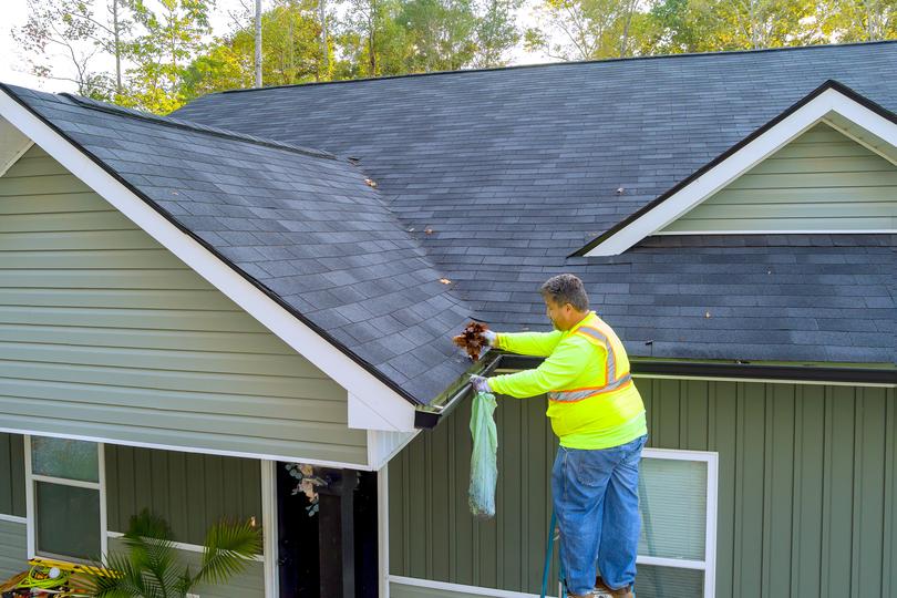 A gutter cleaning professional cleaning gutters on a house