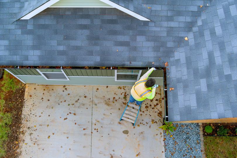 A gutter cleaning professional cleaning gutters on a house